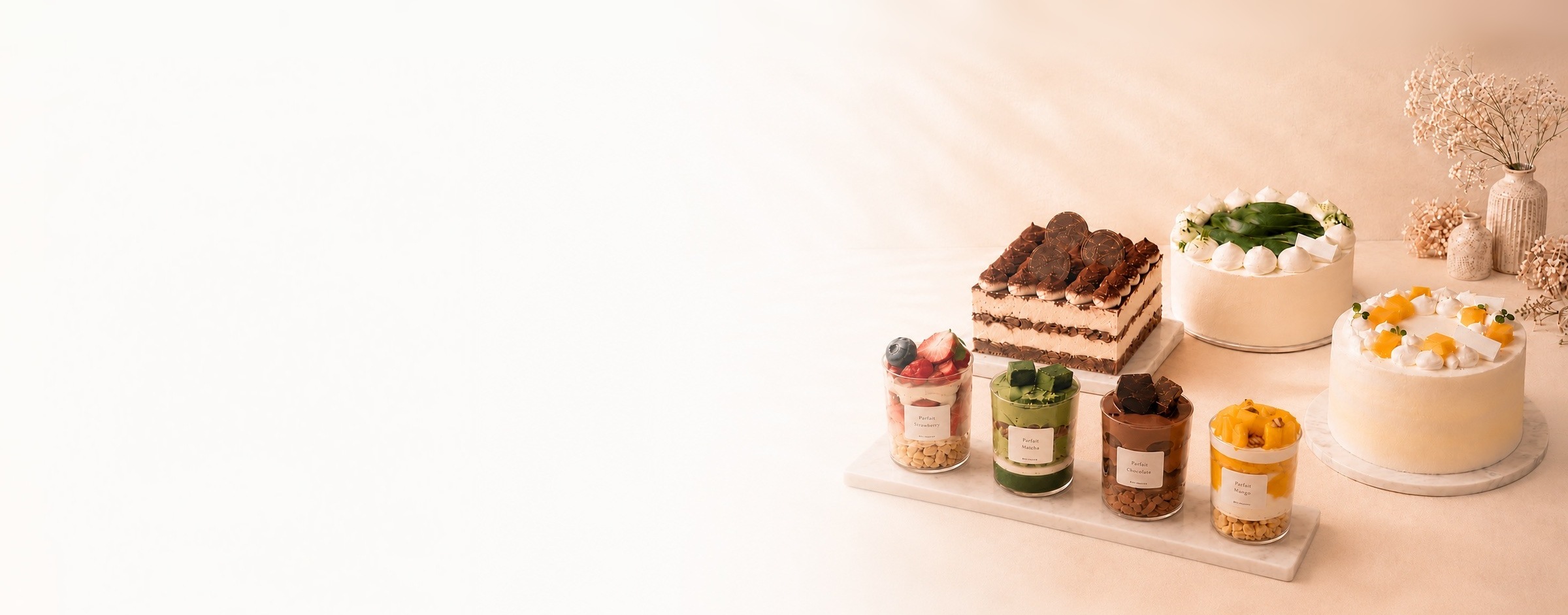 DECI PASTRY cakes and parfait cups arranged in a soft peach studio scene